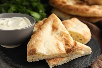 Photo of Cut pita bread, cream cheese and parsley on grey table, closeup