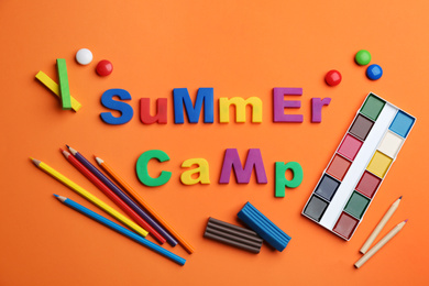 Photo of Flat lay composition with phrase SUMMER CAMP made of magnet letters on orange background