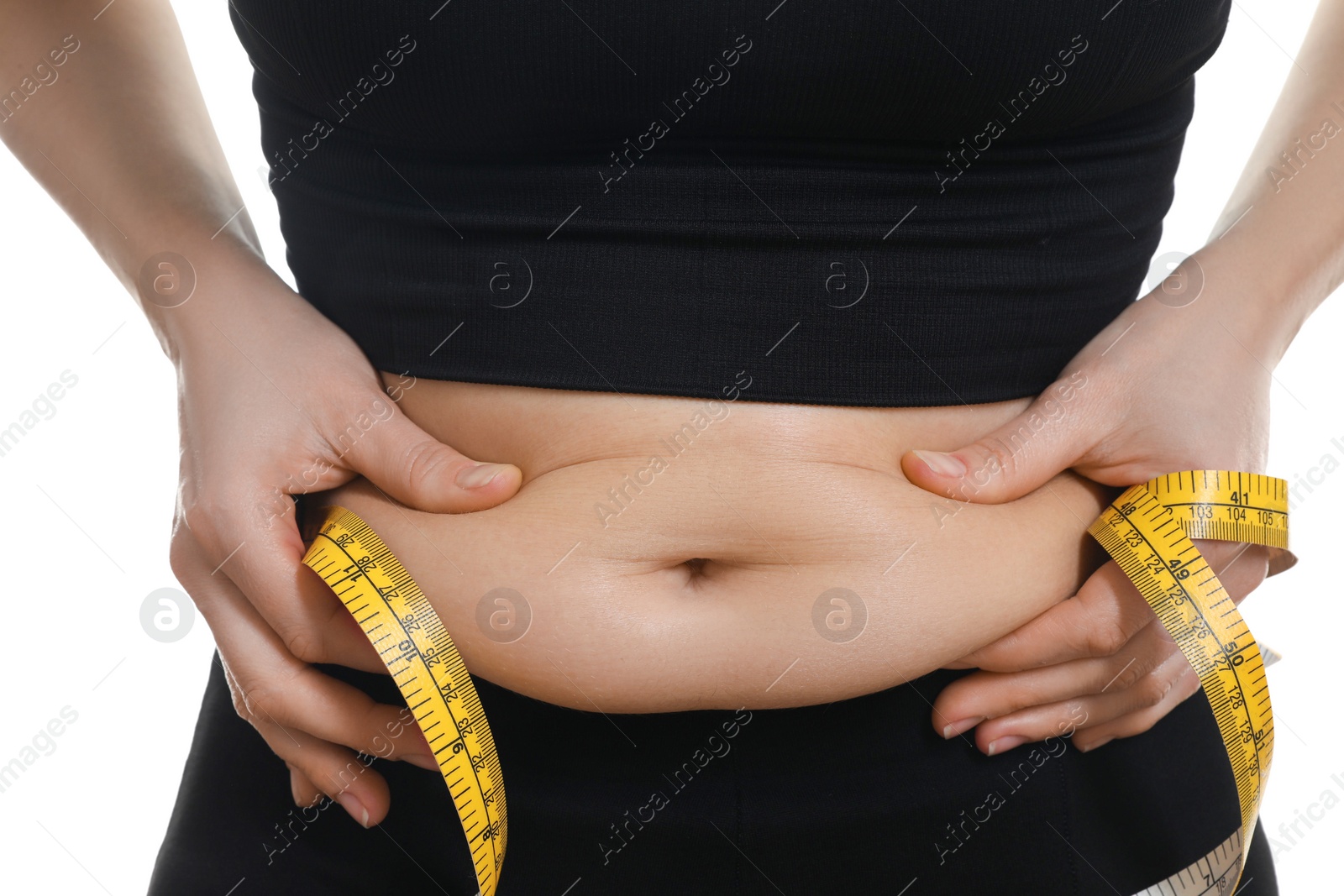 Photo of Woman with measuring tape touching belly fat on white background, closeup. Overweight problem