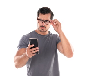 Young man with glasses using mobile phone on white background. Vision problem