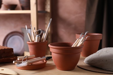 Set of different clay crafting tools on wooden table in workshop