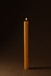 Photo of Burning church wax candle on dark background