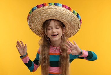 Cute girl in Mexican sombrero hat on orange background