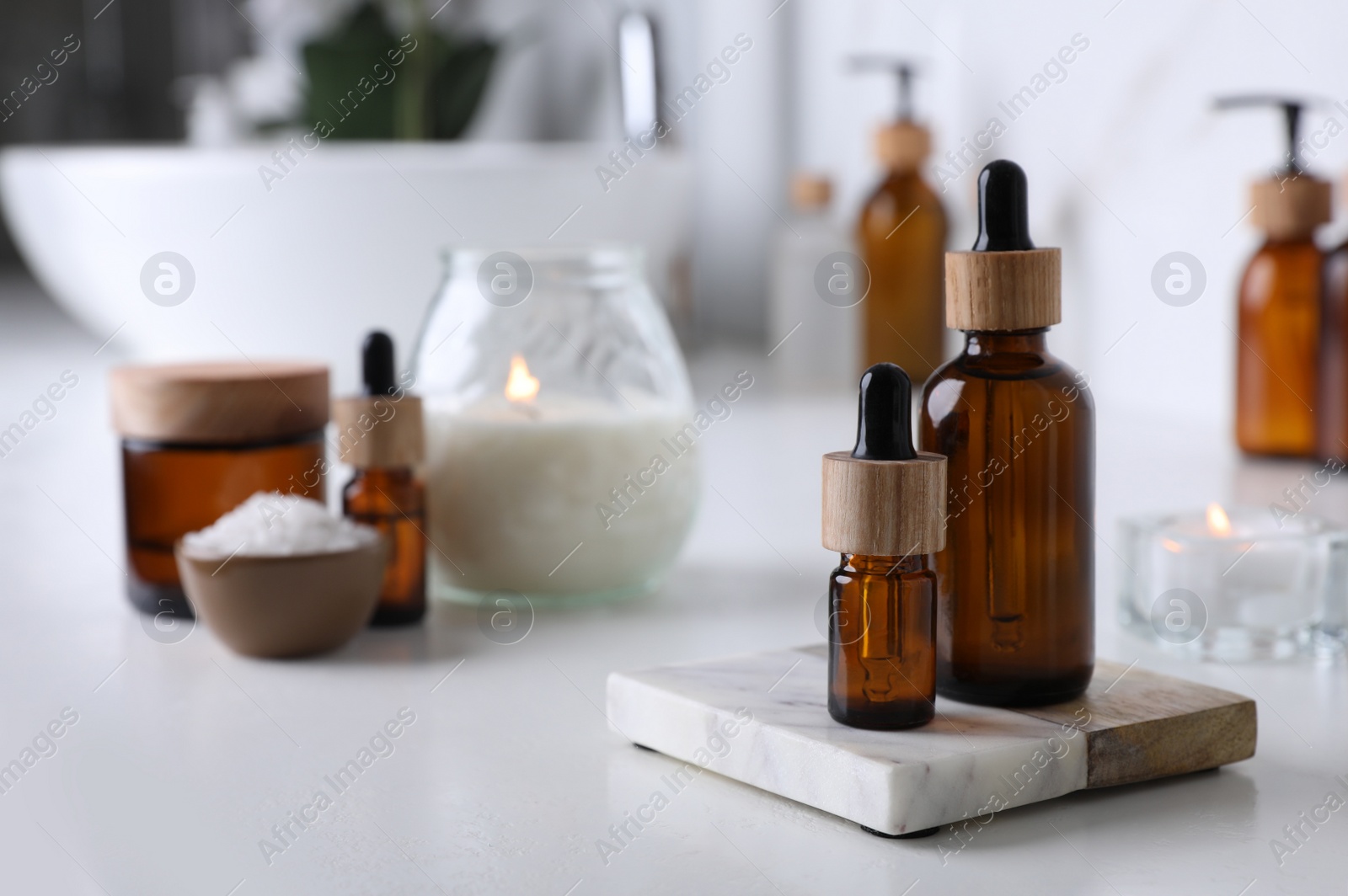 Photo of Essential oils and other cosmetic products on white countertop in bathroom