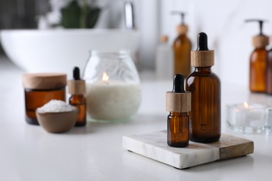 Photo of Essential oils and other cosmetic products on white countertop in bathroom