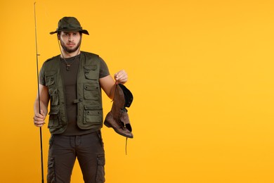 Photo of Fisherman with rod and old boot on yellow background, space for text