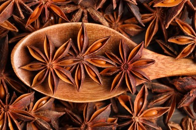 Photo of Aromatic anise stars and wooden spoon on table, closeup