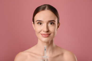 Beautiful woman getting facial injection on pink background. Cosmetic surgery