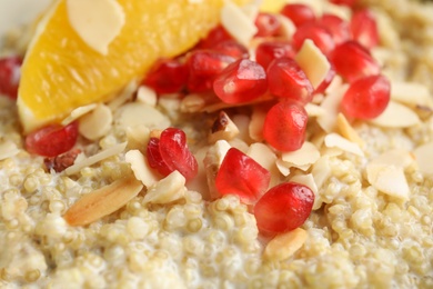 Photo of Quinoa porridge with nuts, orange and pomegranate seeds as background, closeup