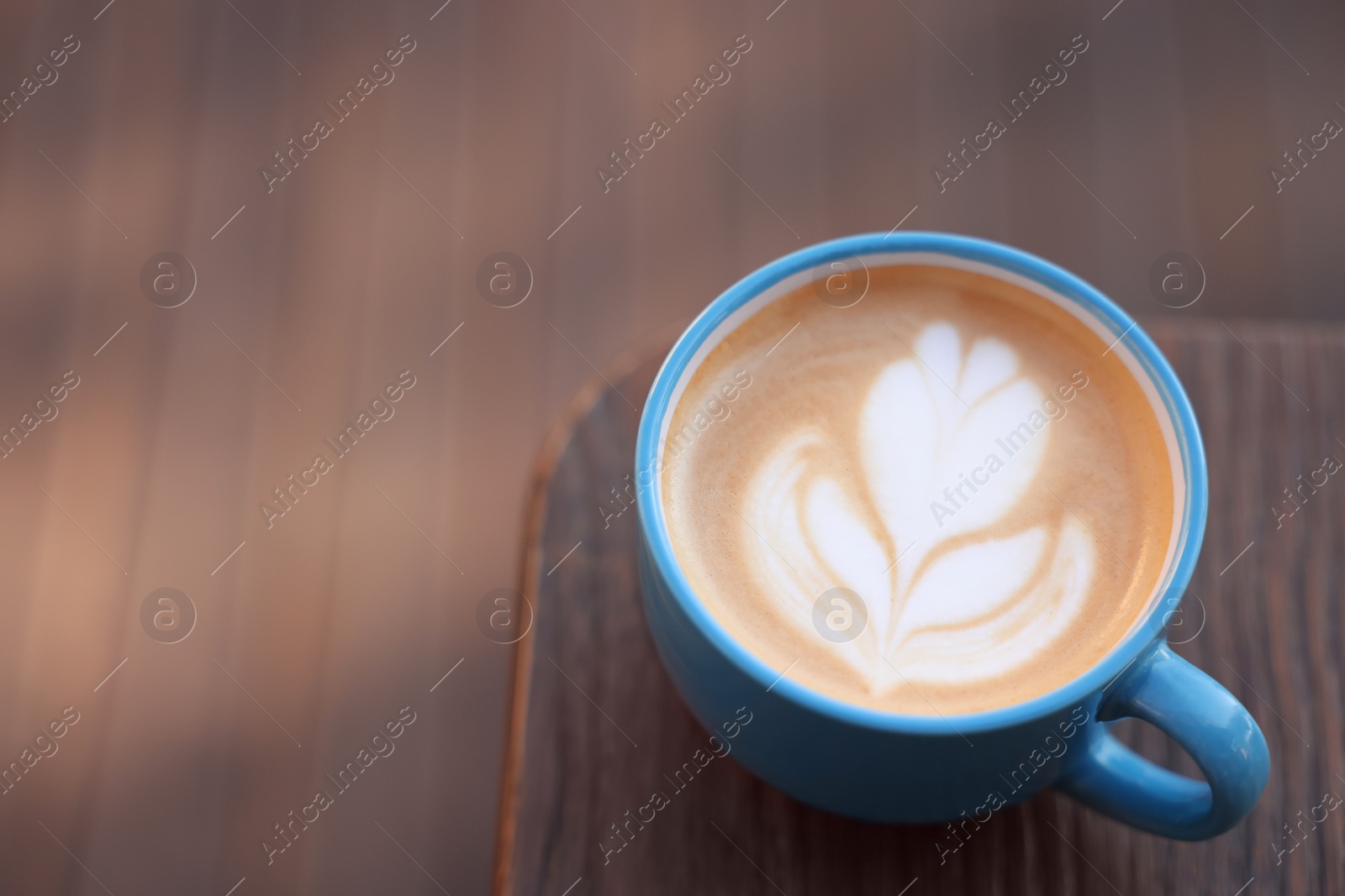 Photo of Ceramic cup of aromatic coffee with foam on wooden table. Space for text