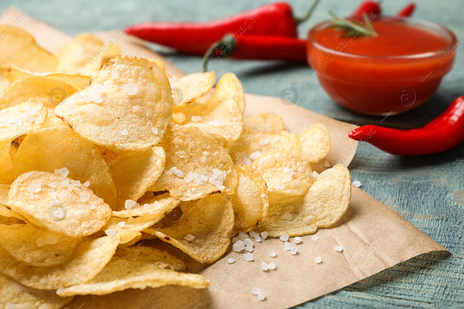 Photo of Delicious crispy potato chips with salt on table, closeup