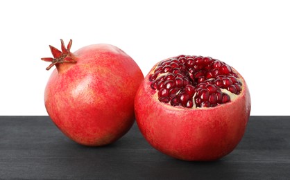 Photo of Fresh pomegranates on black wooden table against white background