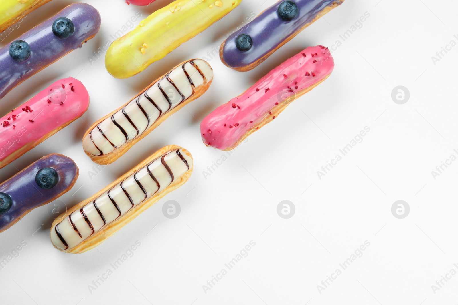 Photo of Delicious eclairs covered with glaze on white background, top view