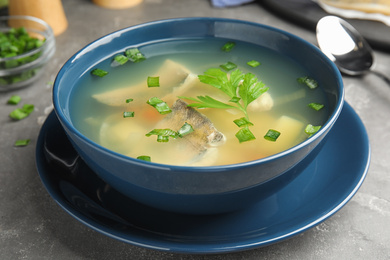 Delicious fish soup served on grey table, closeup