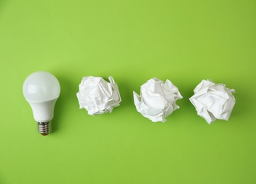 Photo of Flat lay composition with lamp bulb and crumpled paper on color background