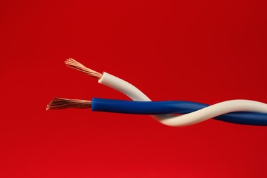 Photo of Two different electrical wires on red background, closeup