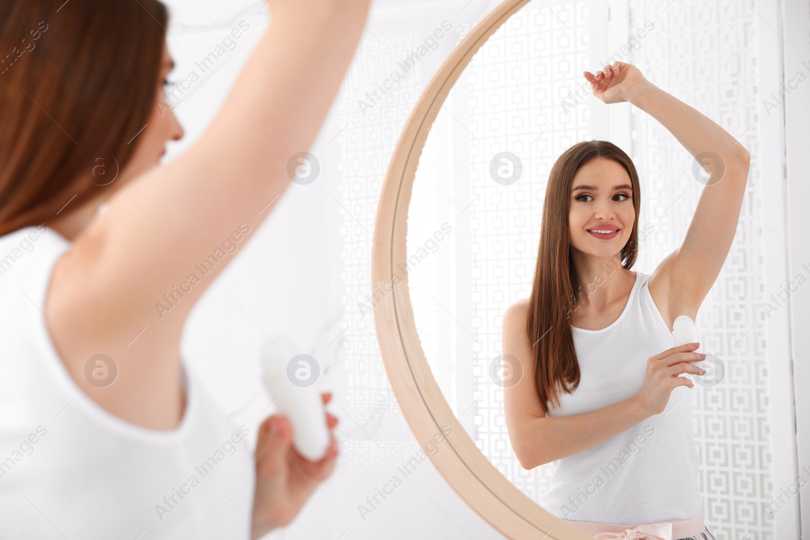 Photo of Beautiful young woman applying deodorant in bathroom