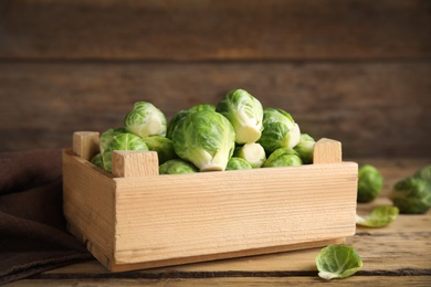 Photo of Crate with fresh Brussels sprouts on wooden table, closeup