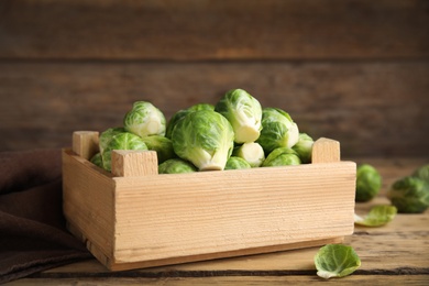 Crate with fresh Brussels sprouts on wooden table, closeup