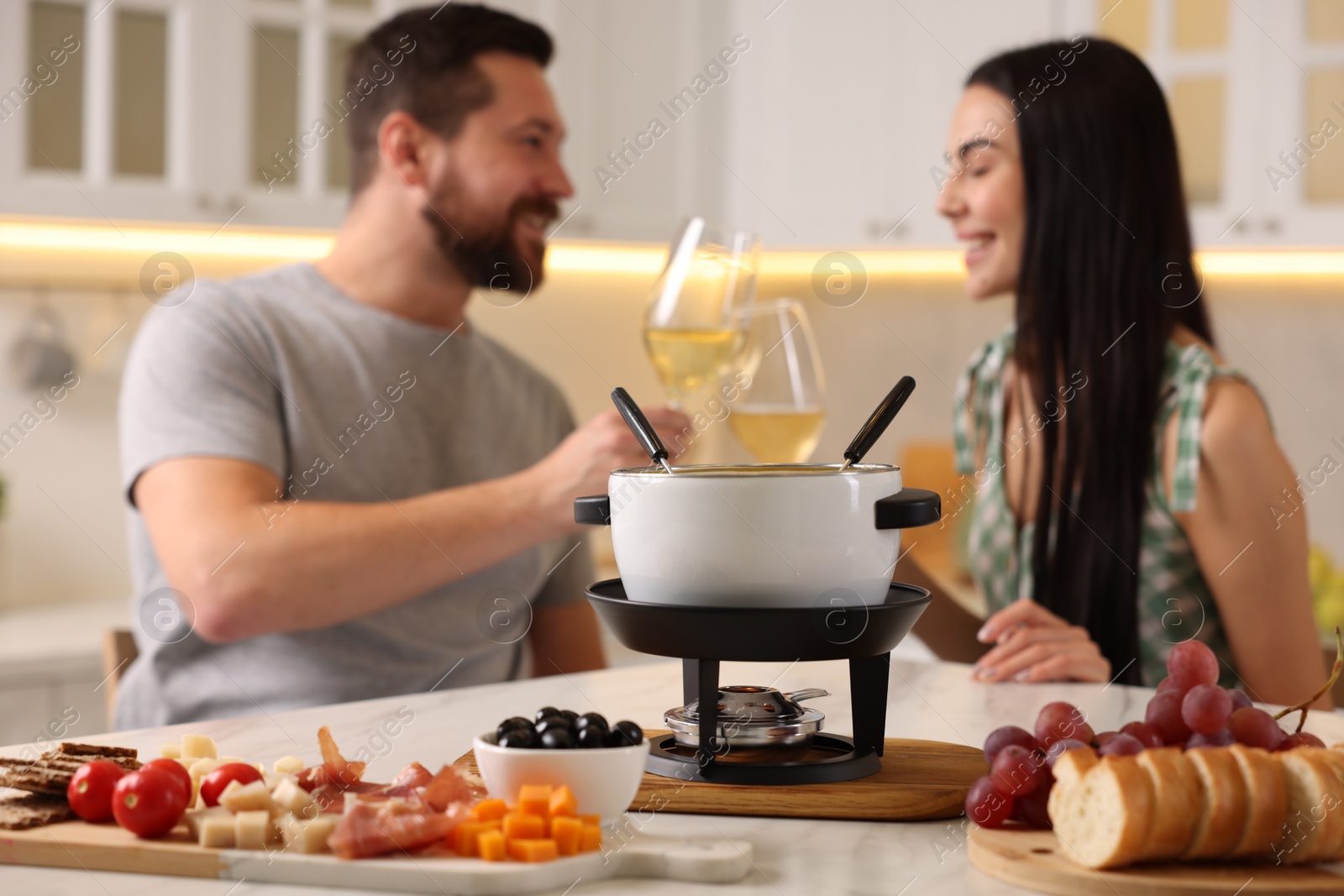 Photo of Couple spending time together during romantic date in kitchen, focus on fondue