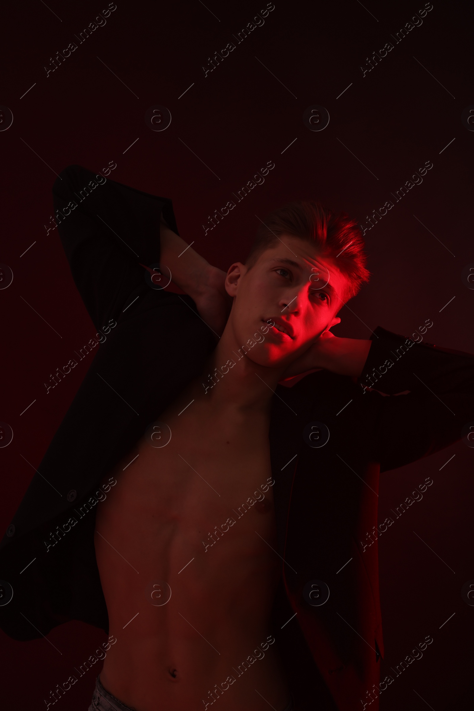 Photo of Sexy young man on dark background in neon light