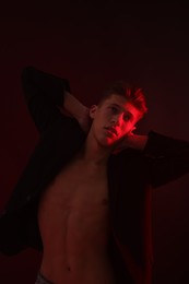 Photo of Sexy young man on dark background in neon light