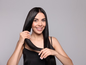 Photo of Portrait of beautiful young woman with healthy strong hair on light grey background