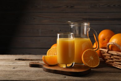 Photo of Tasty fresh oranges and juice on wooden table, closeup. Space for text