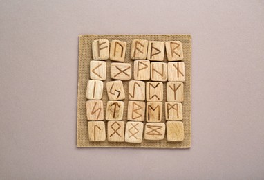 Wooden runes on light grey background, top view