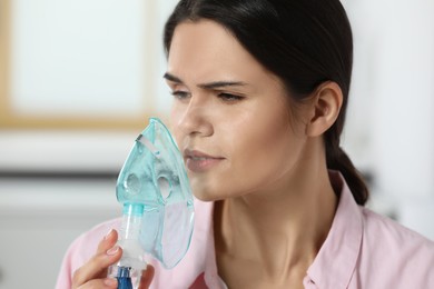 Photo of Sick young woman using nebulizer at home