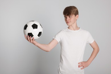 Photo of Teenage boy with soccer ball on light grey background