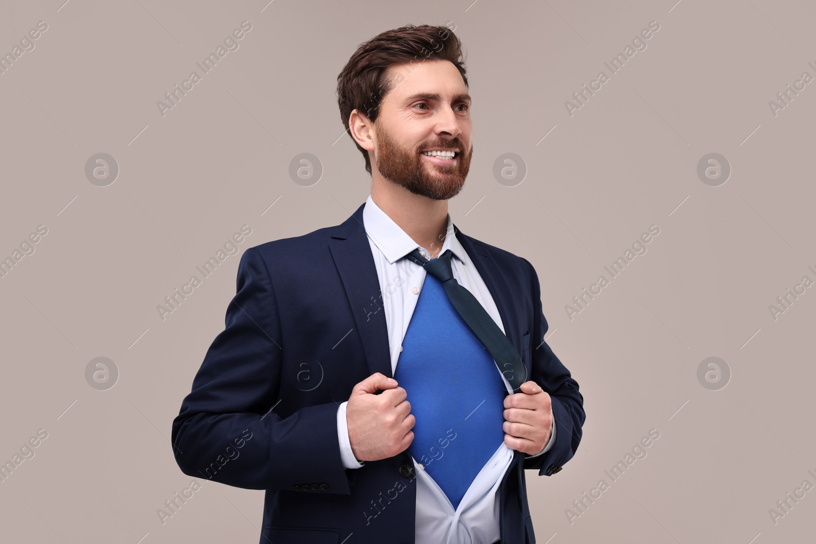 Photo of Happy businessman wearing superhero costume under suit on beige background