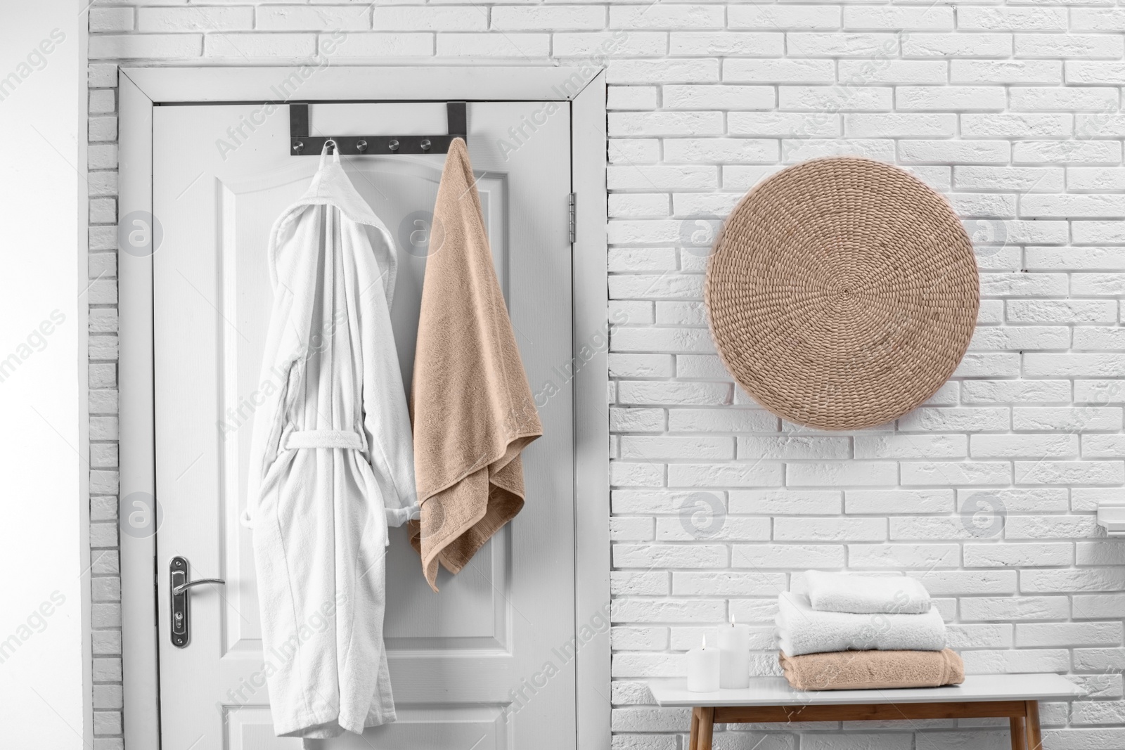 Photo of Soft comfortable bathrobe and towel hanging on door in stylish room interior