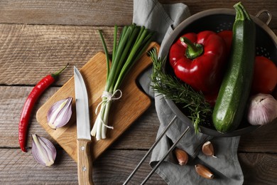 Photo of Cooking ratatouille. Vegetables, rosemary and knife on wooden table, flat lay