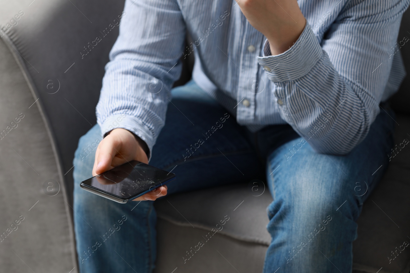 Photo of Man holding damaged smartphone while sitting on armchair, closeup. Device repairing