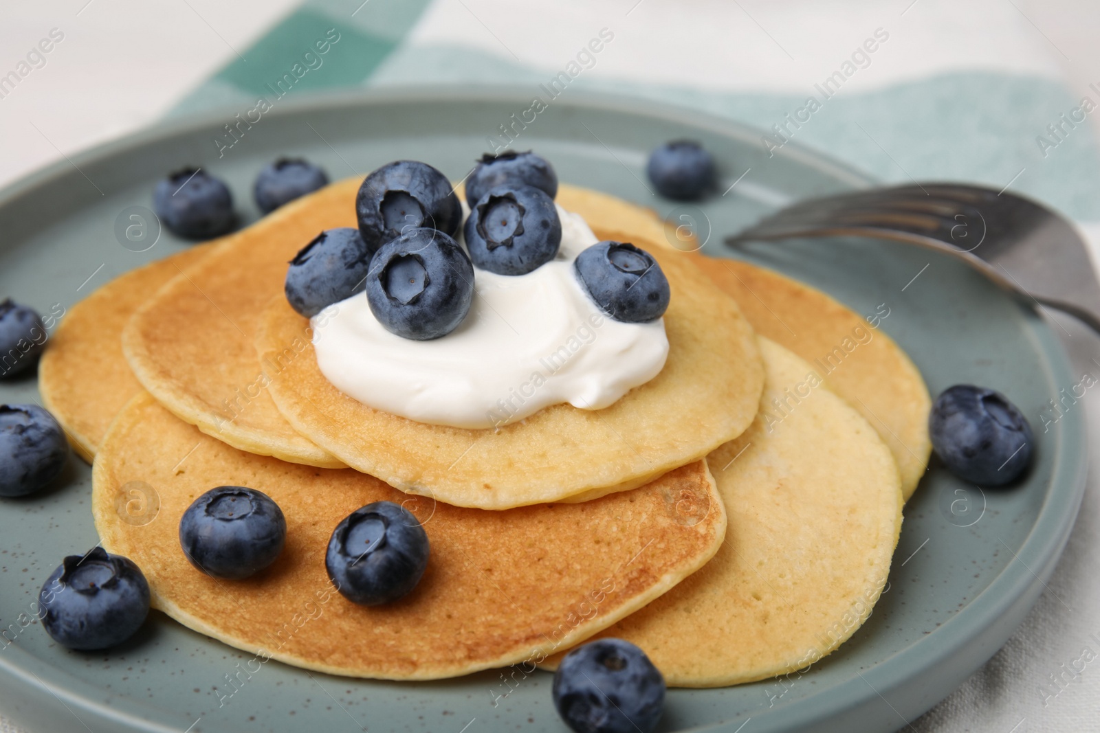 Photo of Tasty pancakes with natural yogurt and blueberries on table, closeup