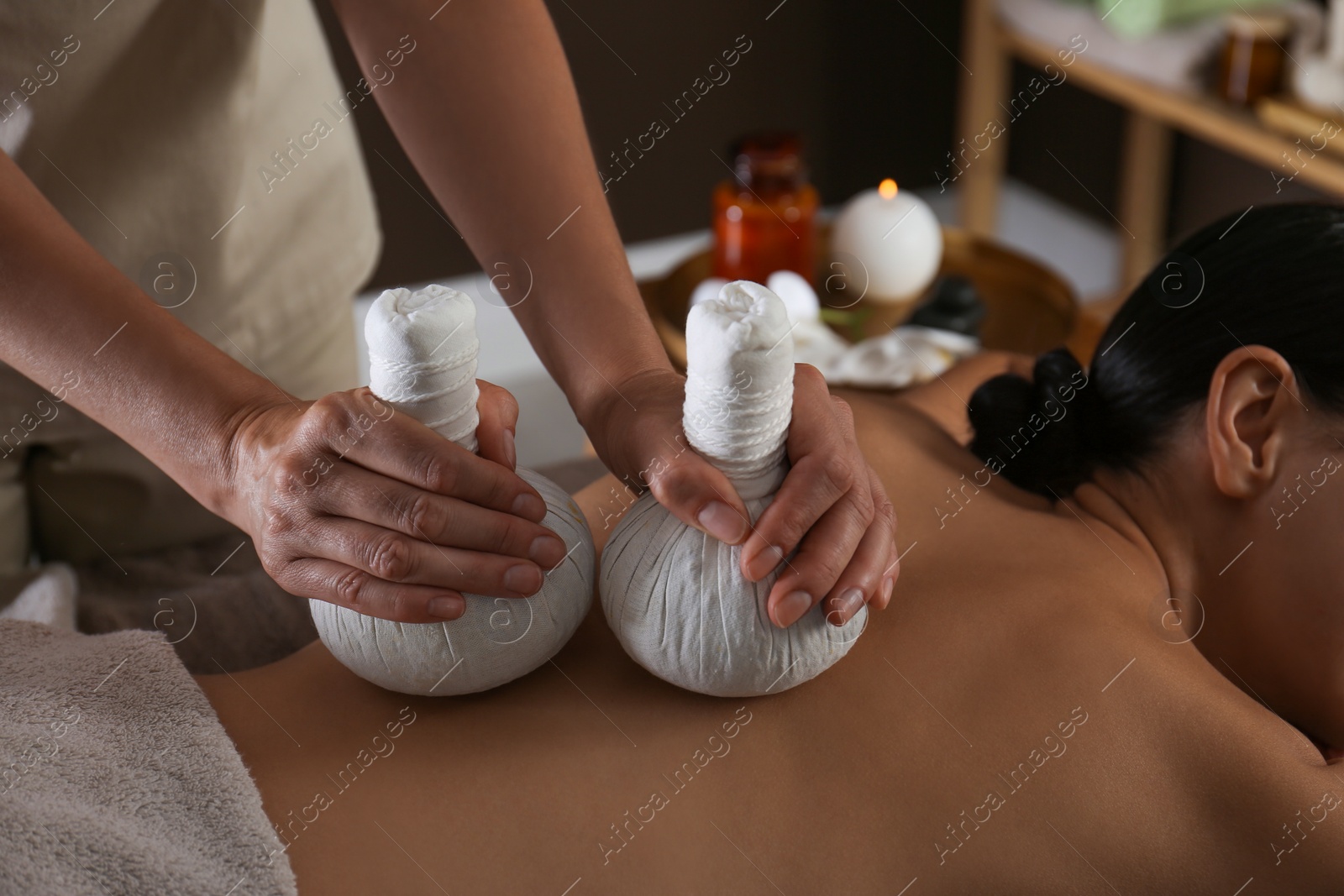 Photo of Young woman receiving herbal bag massage in spa salon, closeup