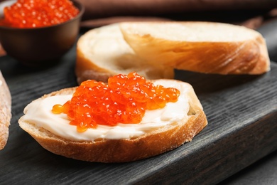 Delicious sandwich with red caviar on wooden board, closeup