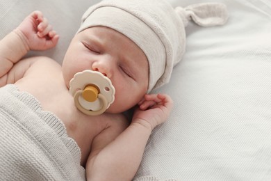 Photo of Adorable little baby with pacifier sleeping in bed, top view. Space for text