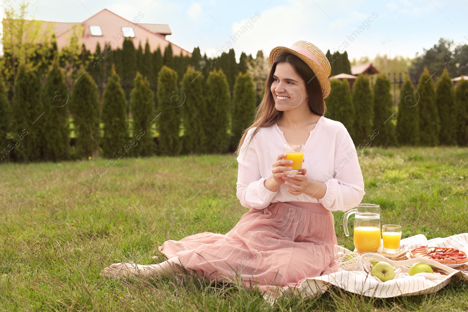 Photo of Young woman with glass of juice having picnic outdoors on summer day