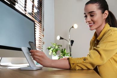 Woman at desk and smartphone on wireless charger. Modern workplace