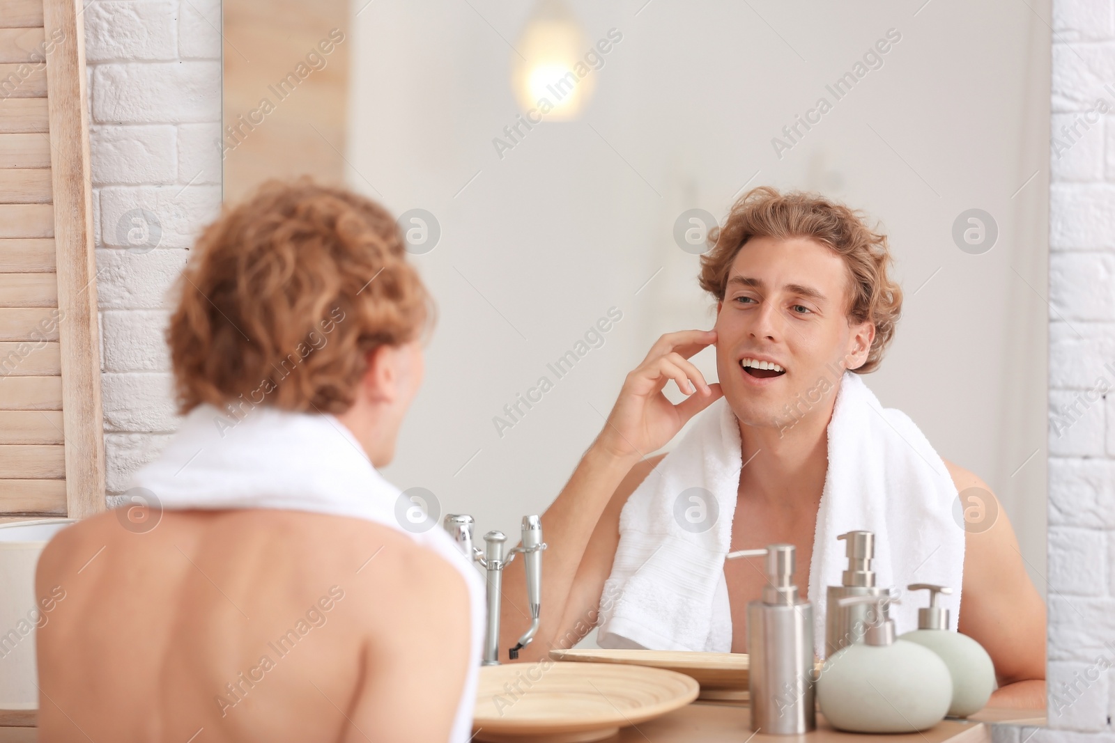 Photo of Young man looking in mirror after shaving at home