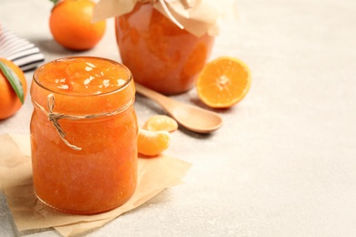 Delicious tangerine jam on light grey table. Space for text