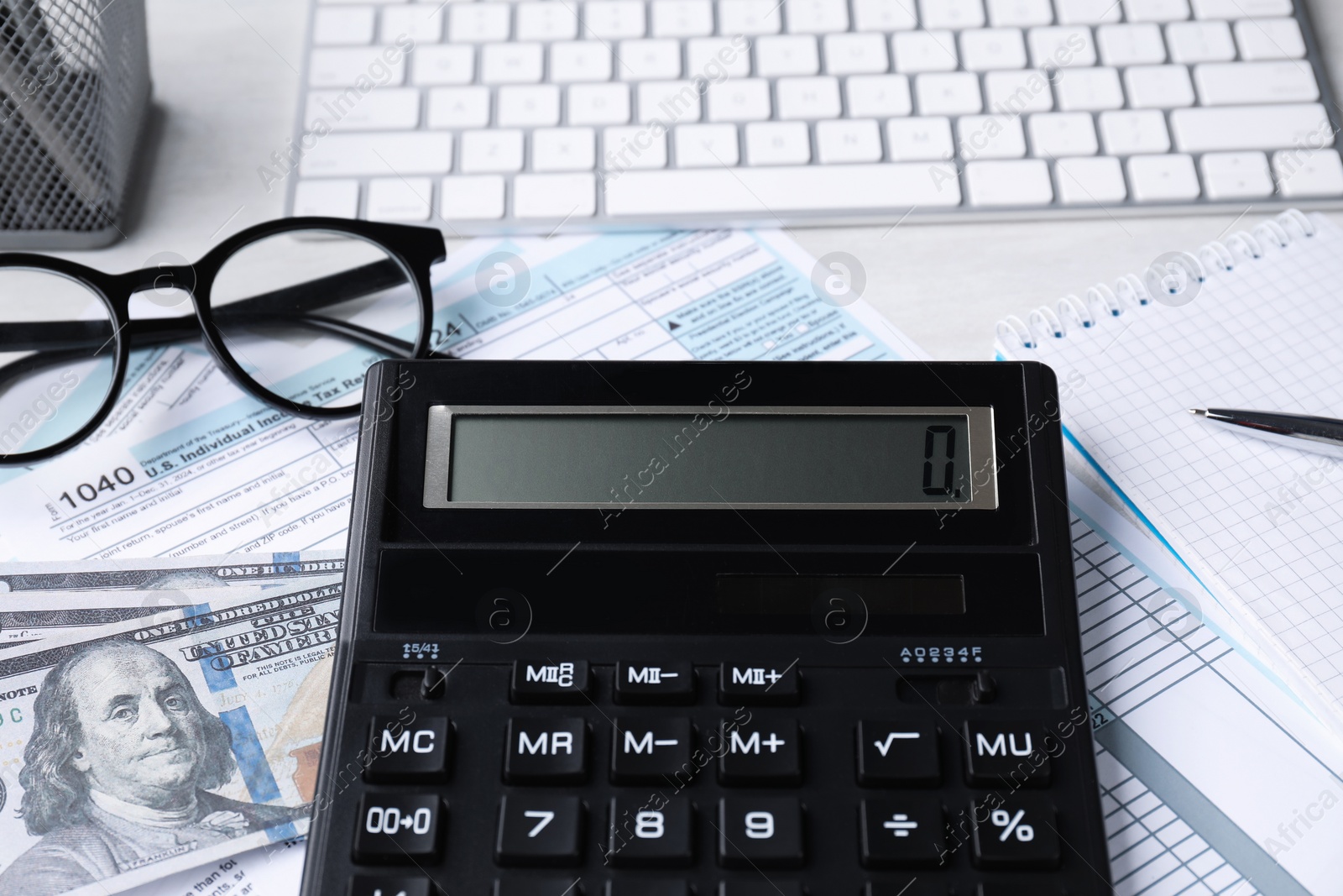 Photo of Tax accounting. Calculator, documents, money, stationery and glasses on light grey table, closeup