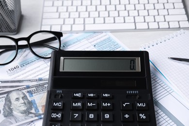 Tax accounting. Calculator, documents, money, stationery and glasses on light grey table, closeup