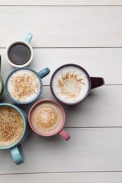 Many different cups with aromatic hot coffee on white wooden table, flat lay