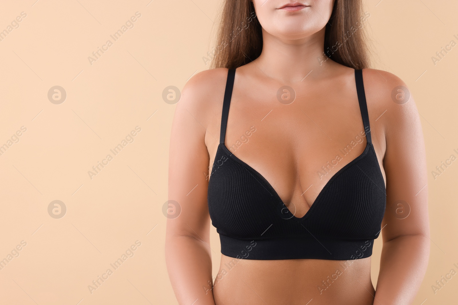 Photo of Woman with beautiful breast on beige background, closeup. Space for text