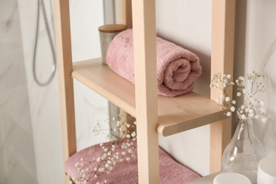 Shelving unit with clean towel in bathroom interior