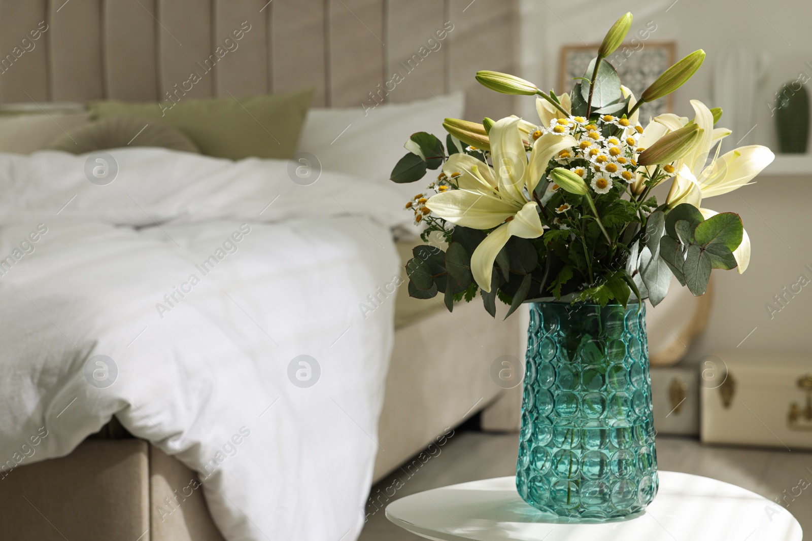 Photo of Bouquet of beautiful flowers on white table in bedroom