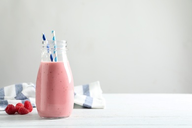 Yummy raspberry smoothie in glass bottle on table. Space for text 